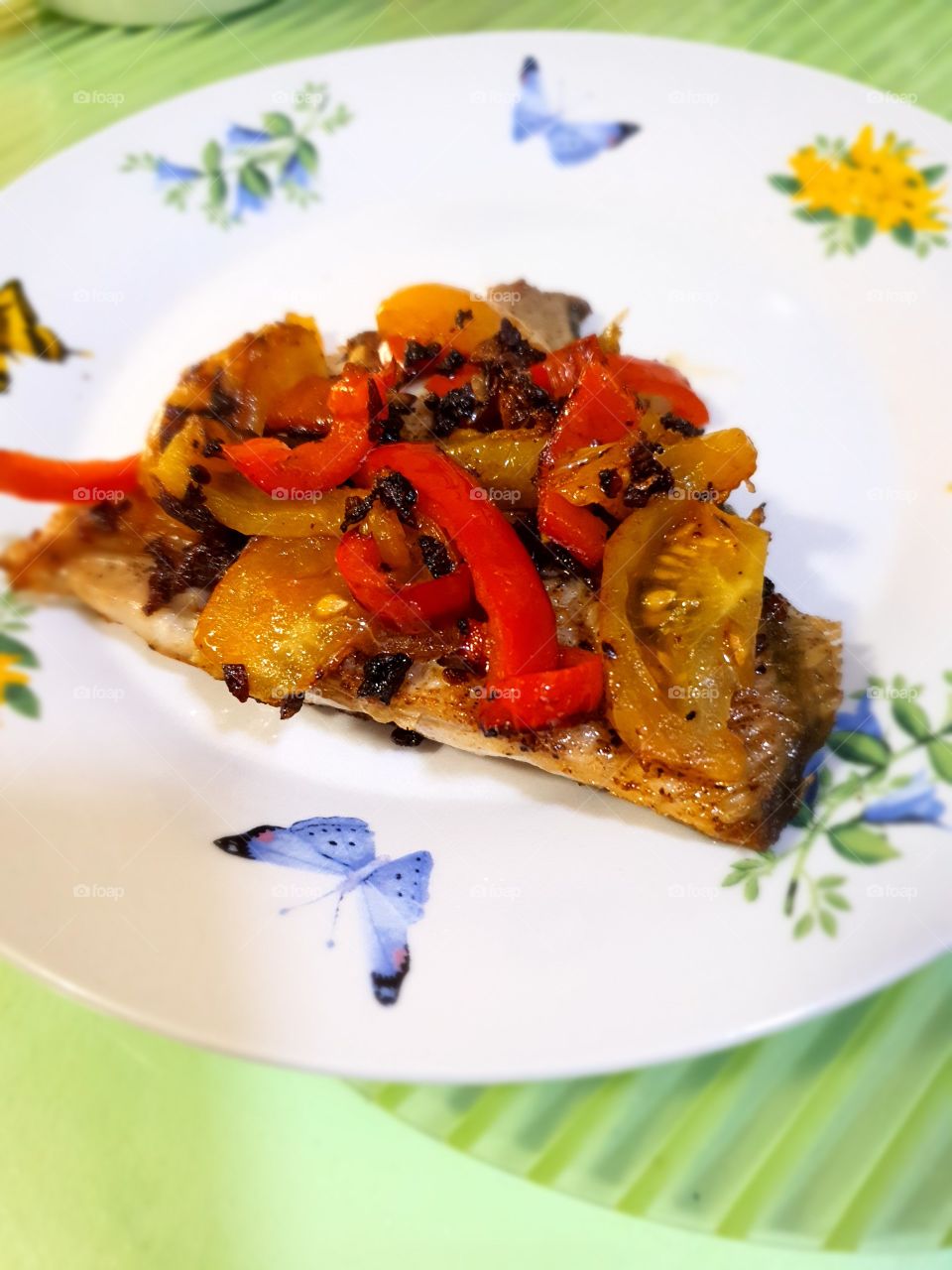 Now serving buttered garlic pompano fish topped with tomatoes and bell pepper..