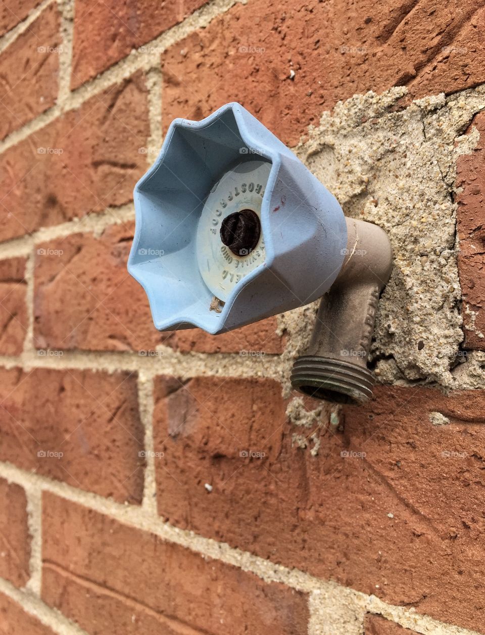 Blue spigot handle on brick building
