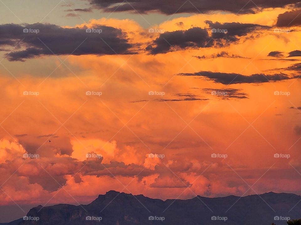 Massive billowing storm clouds gather at sunset over Arizona's Superstition Mountains as a summer storm rolls in