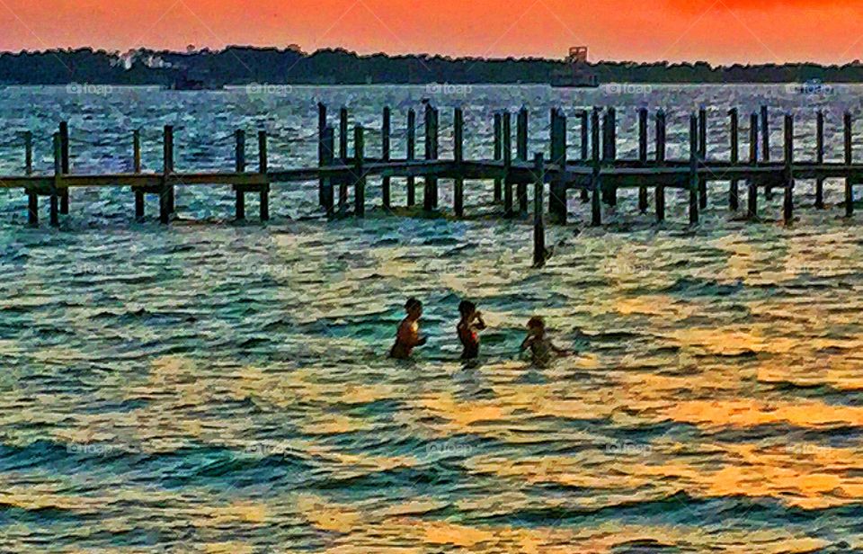 Warm night. Children swimming at sunset