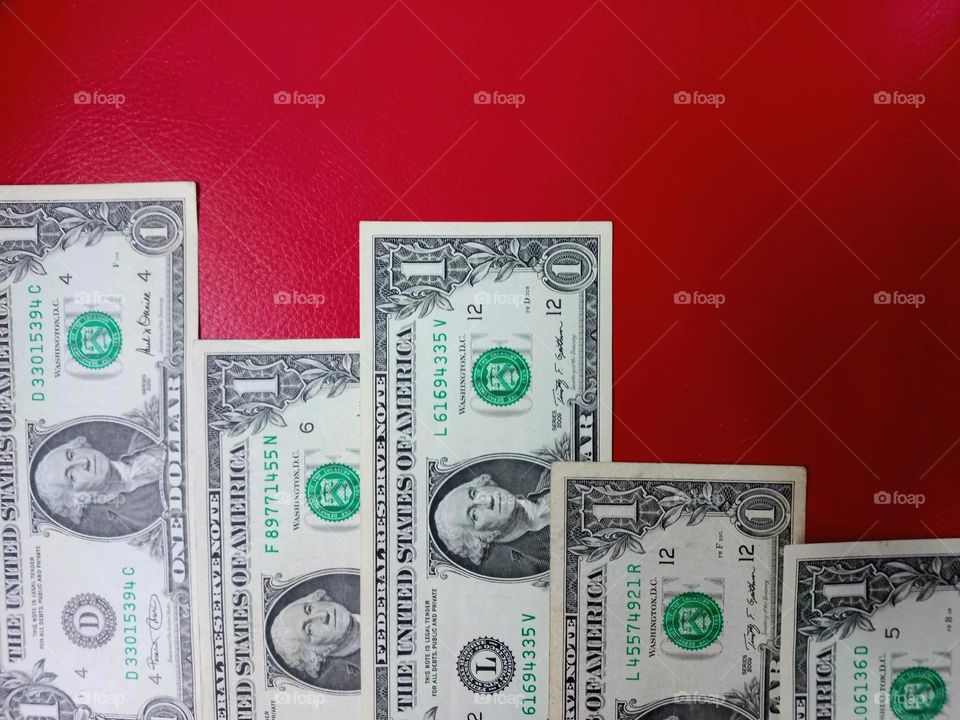spread out dollar bills on a red background.