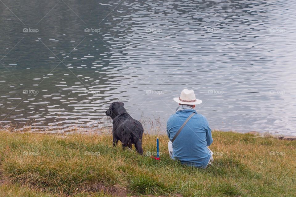 Man and dog on the coast of lake in Rila Mountain