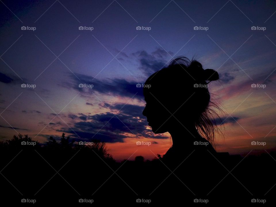 Girl silhouette on sunset background