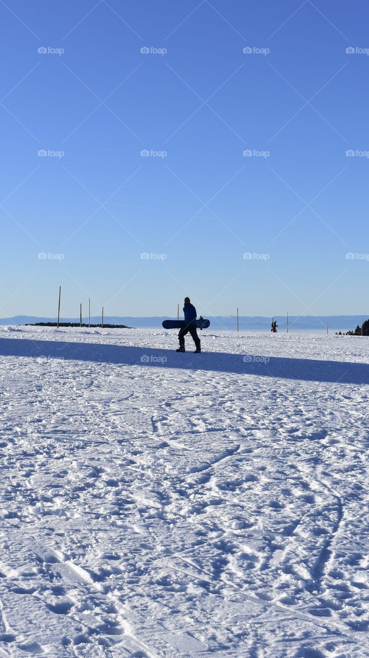 snowboarder walks in the snow with his snowboard