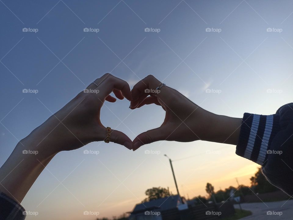 Heart made out of hands on sky background