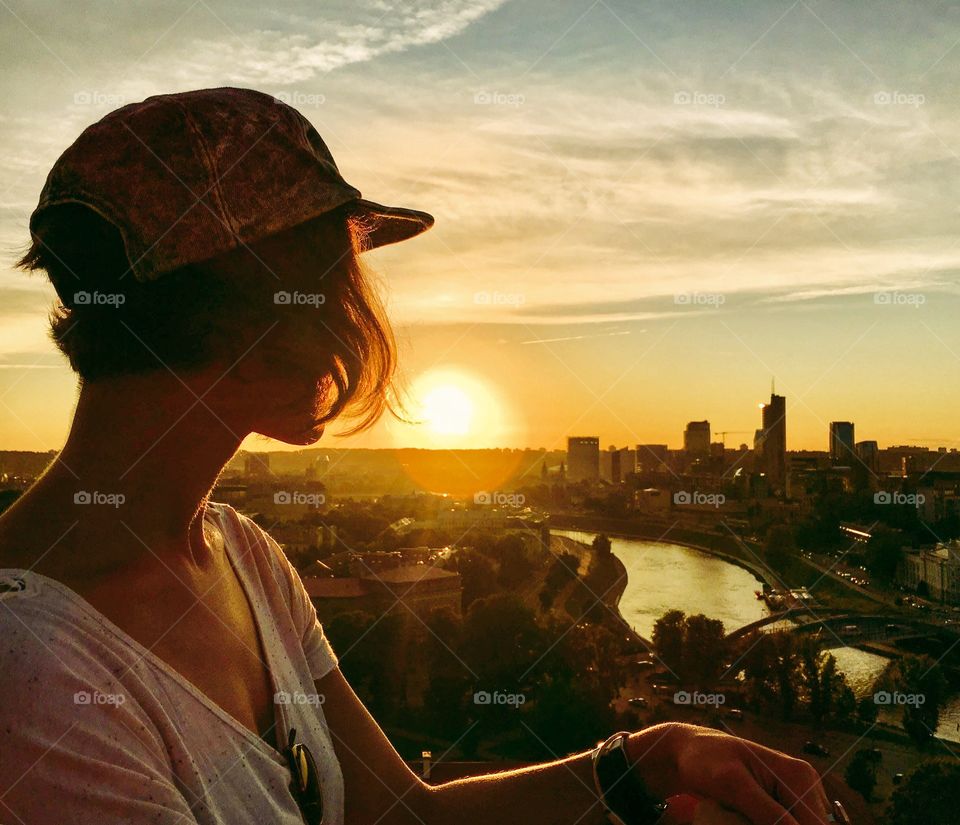 Silhouette of girl enjoying sunset and cityscape of Vilnius from above. 