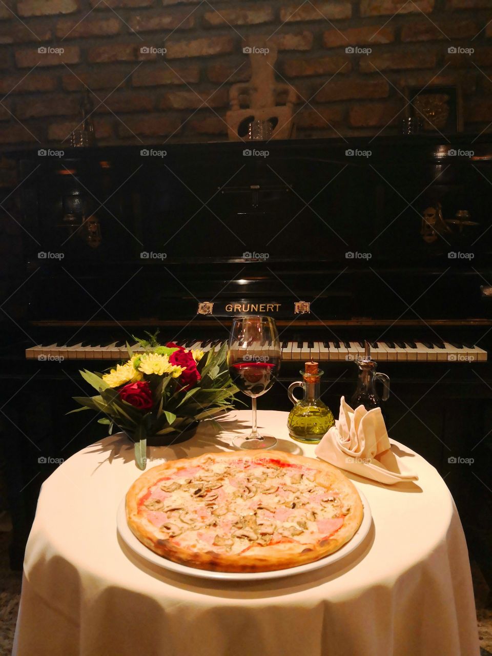 Pizza Capricciosa with glass of red wine and piano of the background.