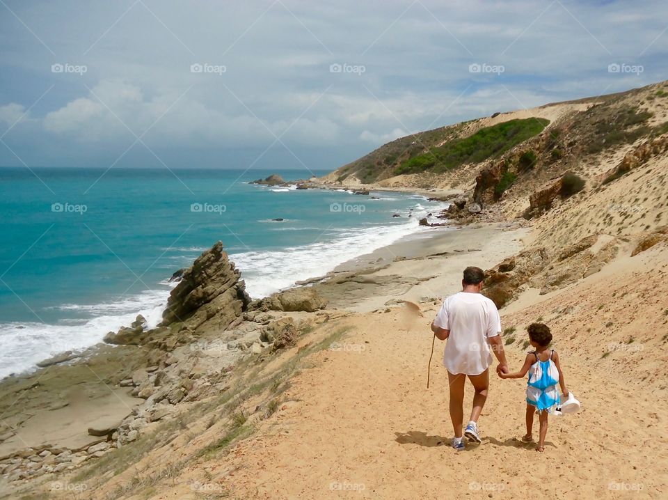 Father and daughter walking on the beach in Jericoacoara, Brazil