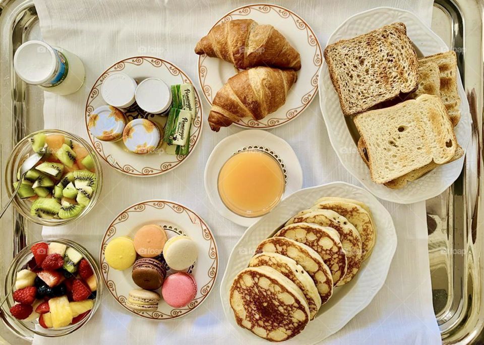 Various assorted breakfast items from above, breakfast flat lay, pancakes and croissants, macarons, toasted bread slices, fruit salad 