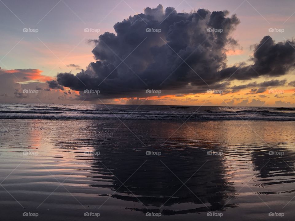 Giant cloud over ocean and sunrise colors