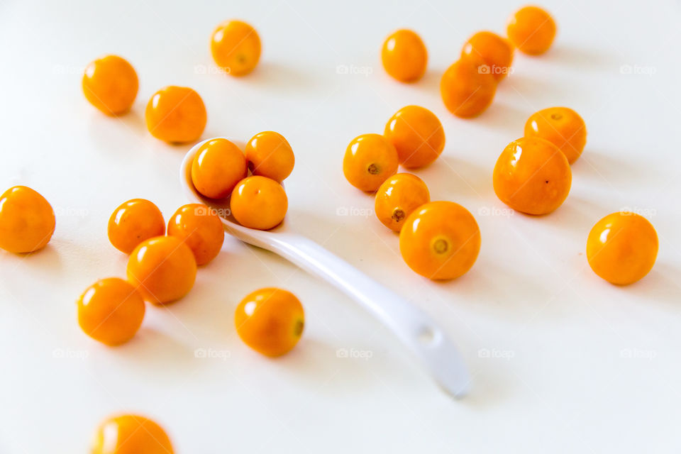 Fresh gooseberry fruits on a white spoon and white background close up. Fresh fruit!