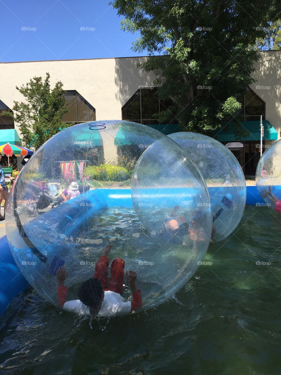 Kids having fun, playing and tumbling in inflatable plastic water walking, rolling balls