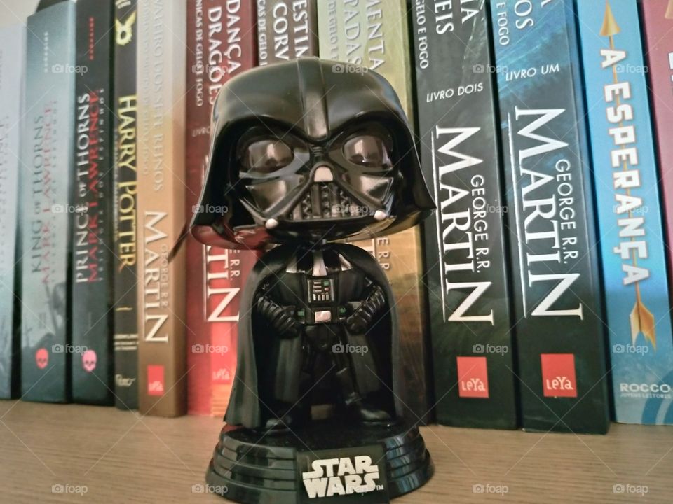 funko Darth Vader com fundo em livros na estante