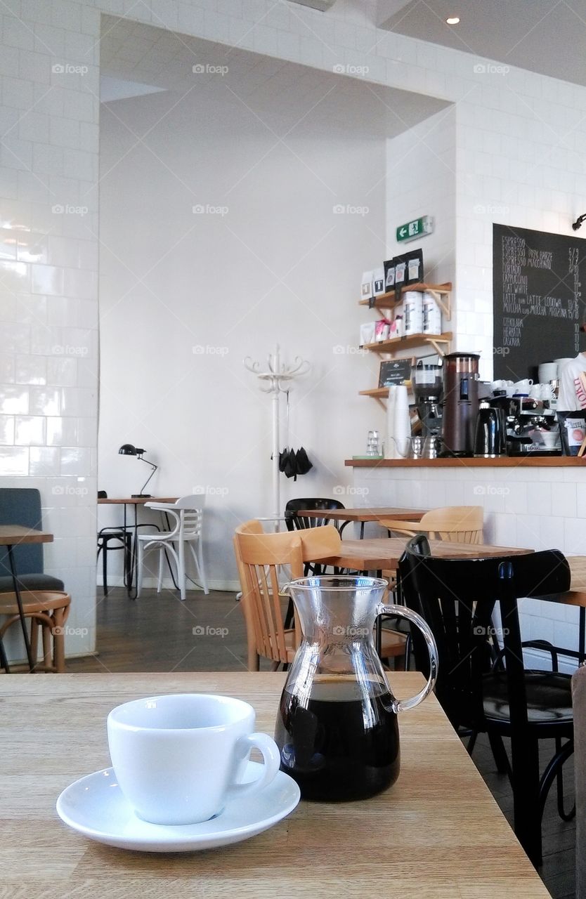 Cup and pot of coffee on the wooden table in cafe