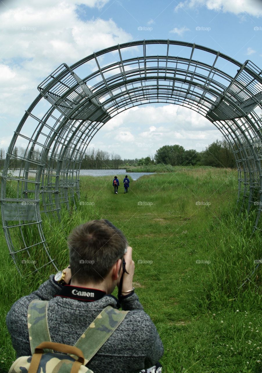 A photographer before a artwork in the meadow in Holland.