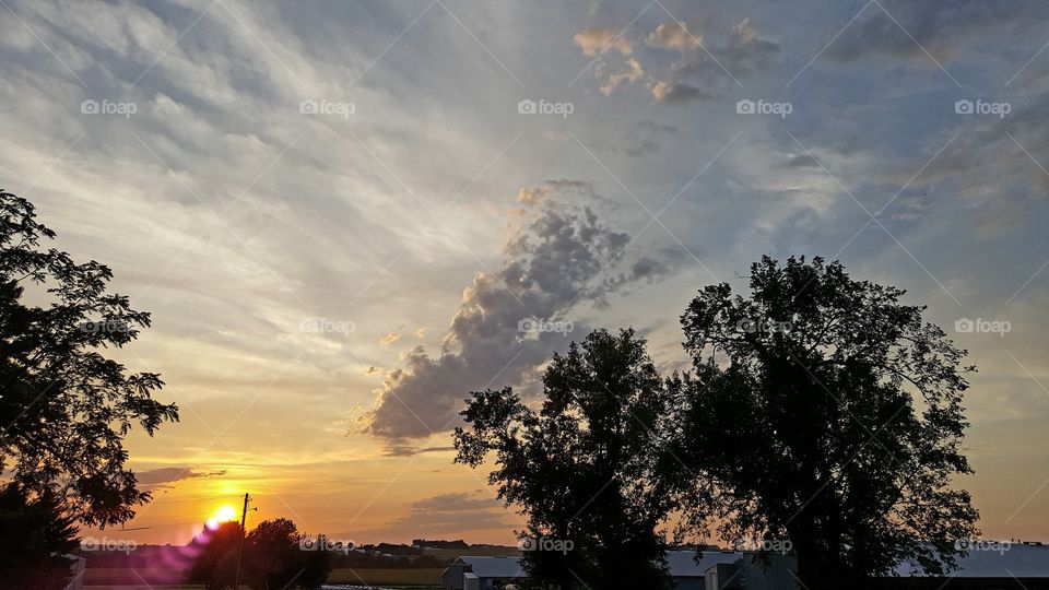 sunset with clouds and trees over turkey barns