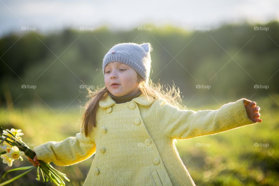 Little girl with narcissus bouquet in spring park