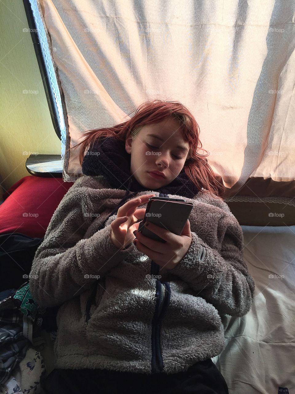 Girl using the phone in the caravan bed