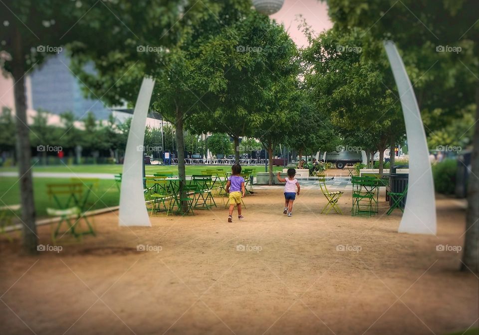 Two small girls running in a Dallas Texas park in summer