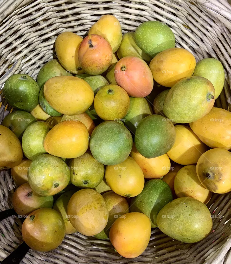 Baby mangoes or mangos inside a basket on sale at fruit market 
