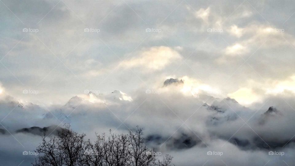 Magnificent mountain peaks of Alaska wrapped in storm clouds at sunset.