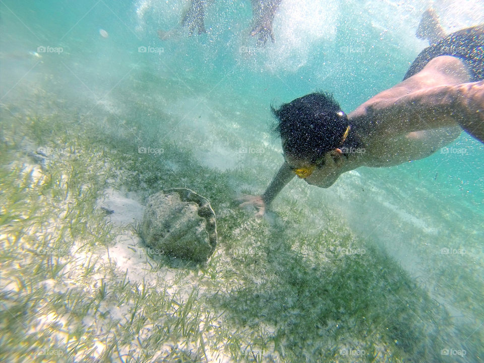 Man swimming exploring underwater looking for big clam