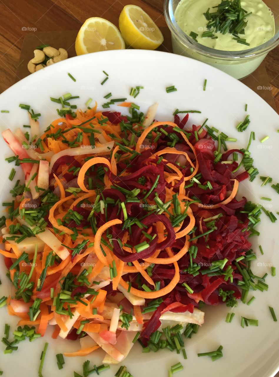 Organic vegan steamed salat with cashew-chives dressing, spaghetti carrots, beetroots, red onions and celeriac.