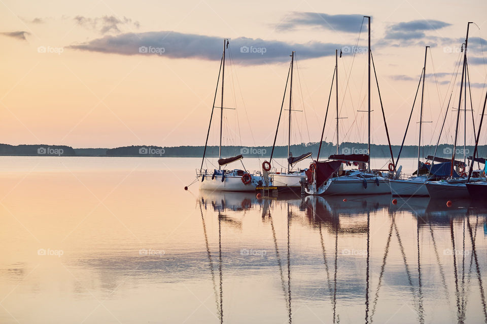 Yachts and boats moored in a harbour at sunrise. Candid people, real moments, authentic situations