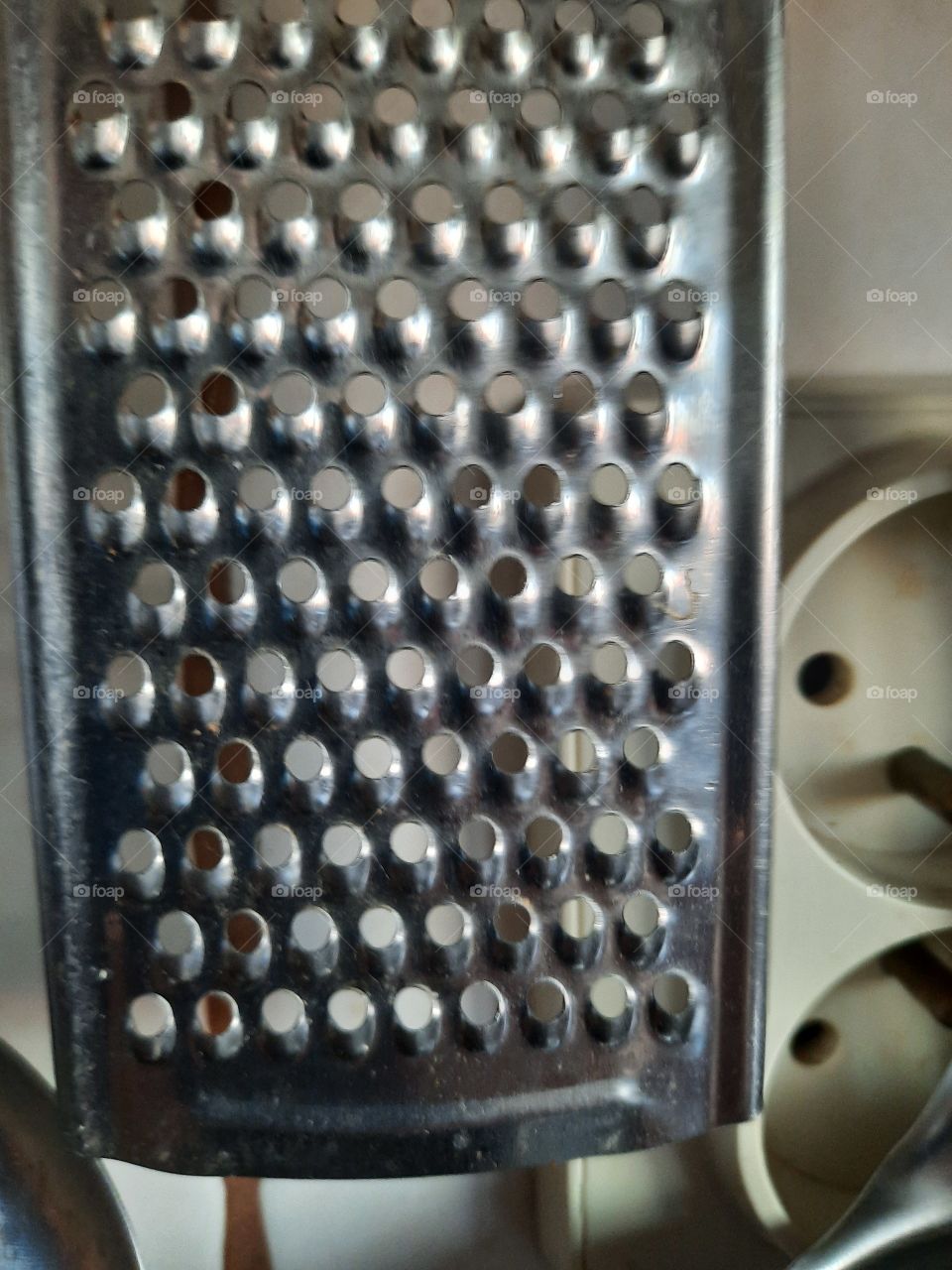 close-up  of metal kitchen grater hanging above the stove