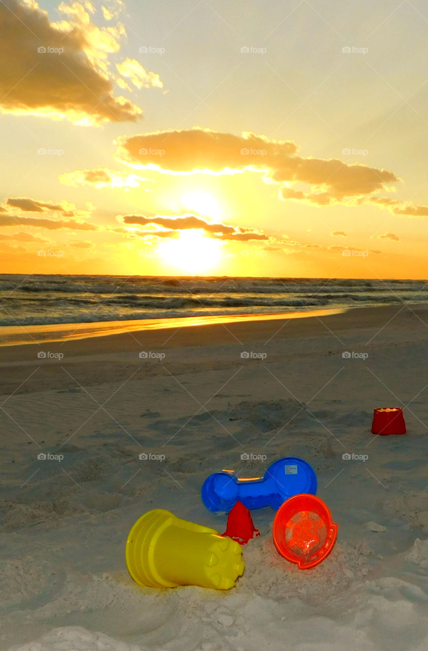 Vacated! 
Children vacate their sand toys on the beach in front of a magnificent sunset! 
These are a collection of my Beautiful Sunsets that I would like to share with you! They are a reminder of the beauty of our natural world! We all have a connection and should stop, take a big breath, and be aware that the earth needs to be protected! My photographs show the strength and the volatile beauty of the sunsets that surround us! Life is good! Enjoy!