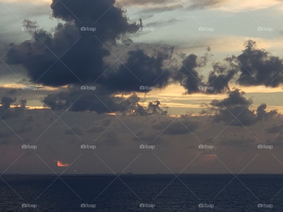 sun behind clouds and the ocean