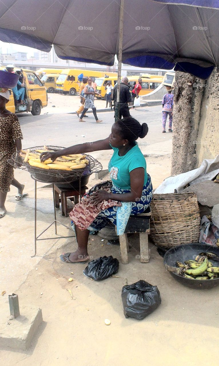 A trader selling roasted plantain in the streetof Lagos State, Nigeria.