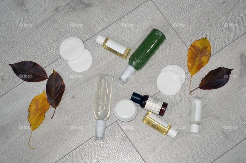 Jars with cream, shampoo and cosmetics on a background with autumn leaves