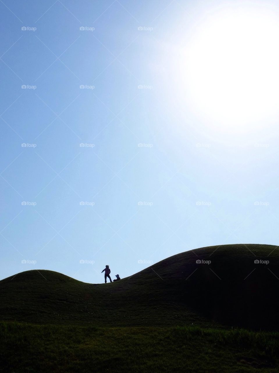 Silhouette of 2 persons on a rolling hill
