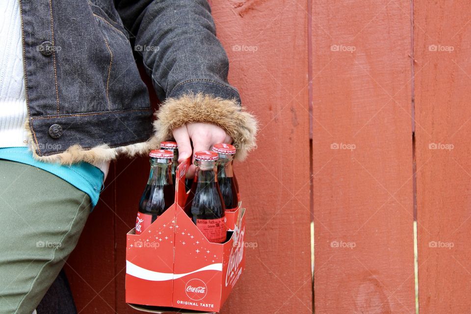 Holding a 6 pack of Coca Cola Bottles 