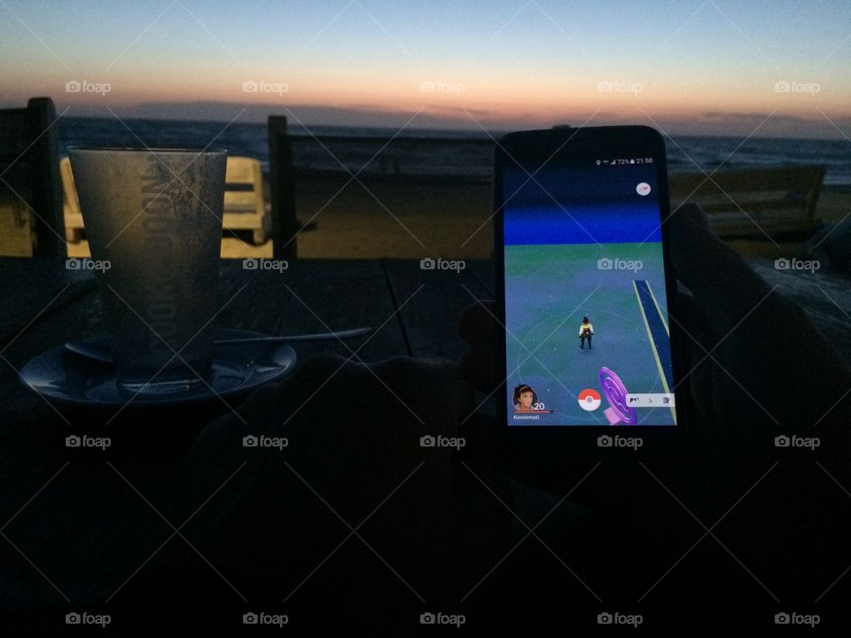 Playing Pokemon Go at the beach at sunset. 