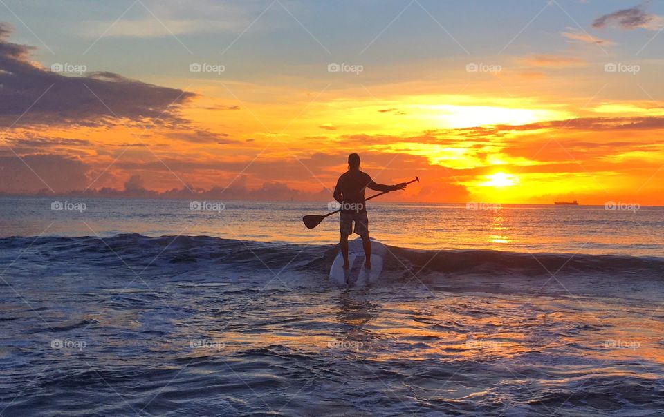 Man surfing in sea during sunrise