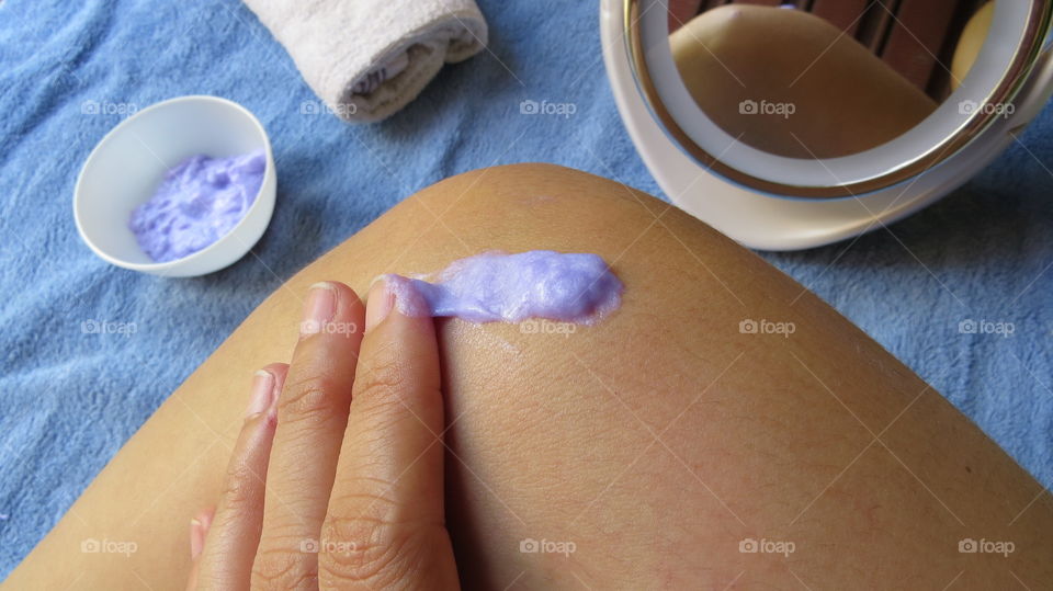 Woman applying moisturizer on leg