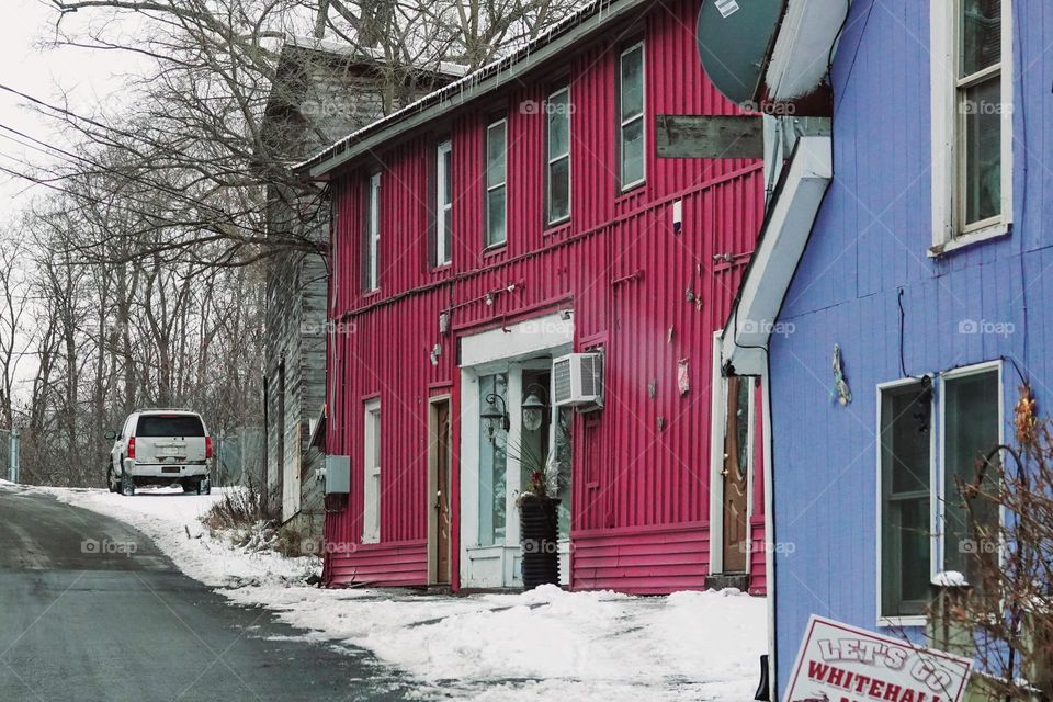 A magenta house adds color to a drab wintery scene on a calm road in the northeast US