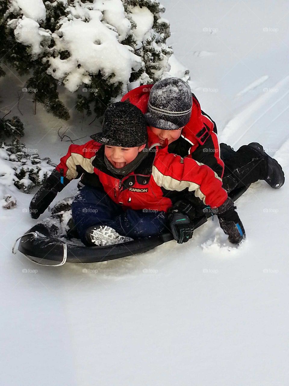 Two boys sliding on snow having big fun