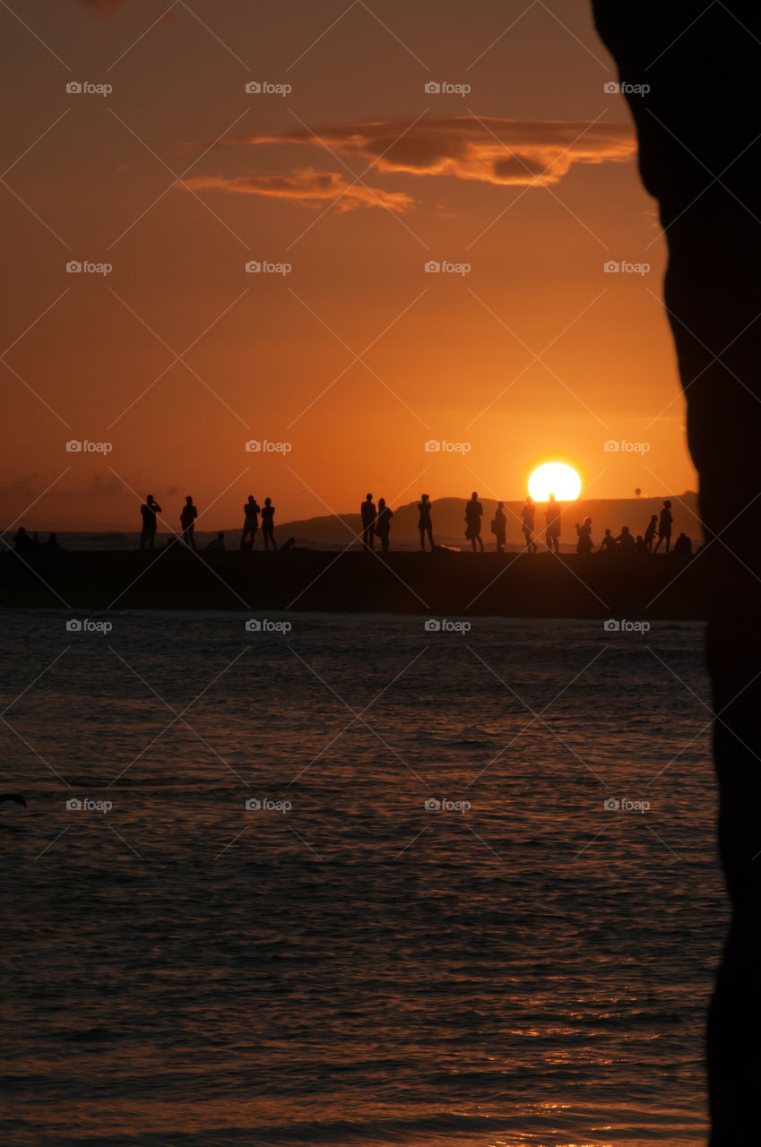 Spectators at a distance watching a beautiful Hawaii sunset.