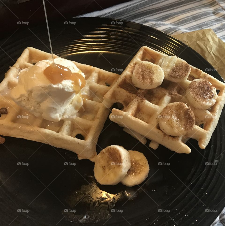 A Yummy breakfast of waffles with ice cream drizzled with Caramel syrup with bananas and cinnamon on top. USA, America 