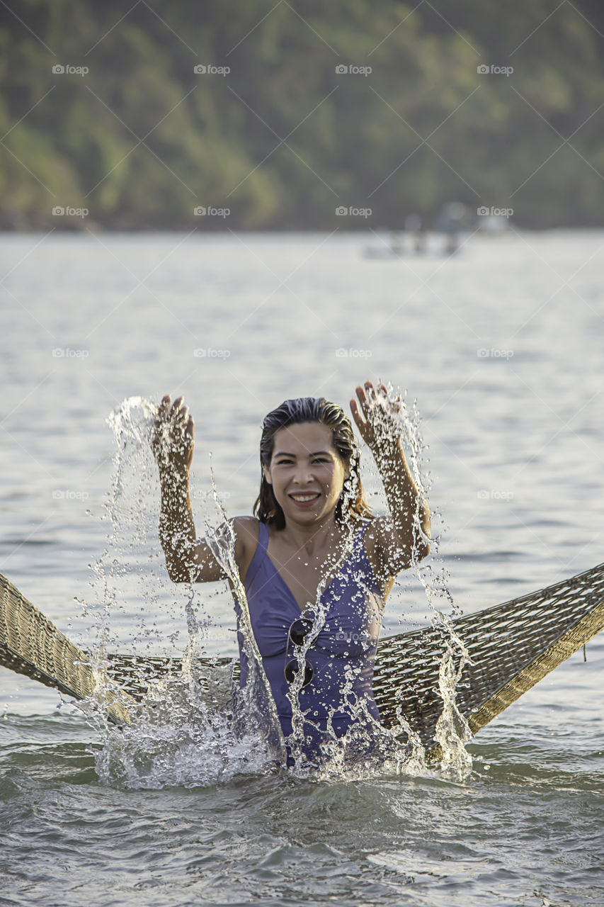 Portrait of Asian woman wearing a swimsuit on Hammock swing in sea.