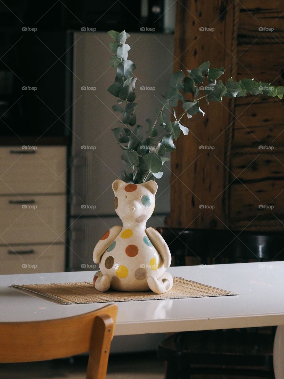 Eucalyptus branches stand in the shape of a bear on a wooden table in a cozy kitchen