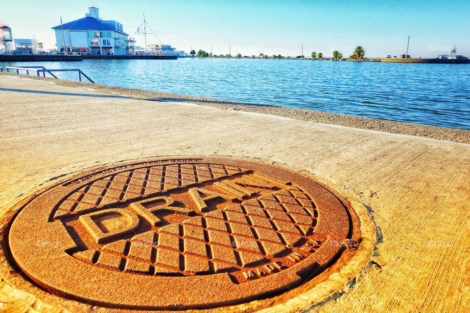 Rusty cast iron footpath drain plate. Along the pedestrian walkway of Lake Pontchartrain, New Orleans, USA.