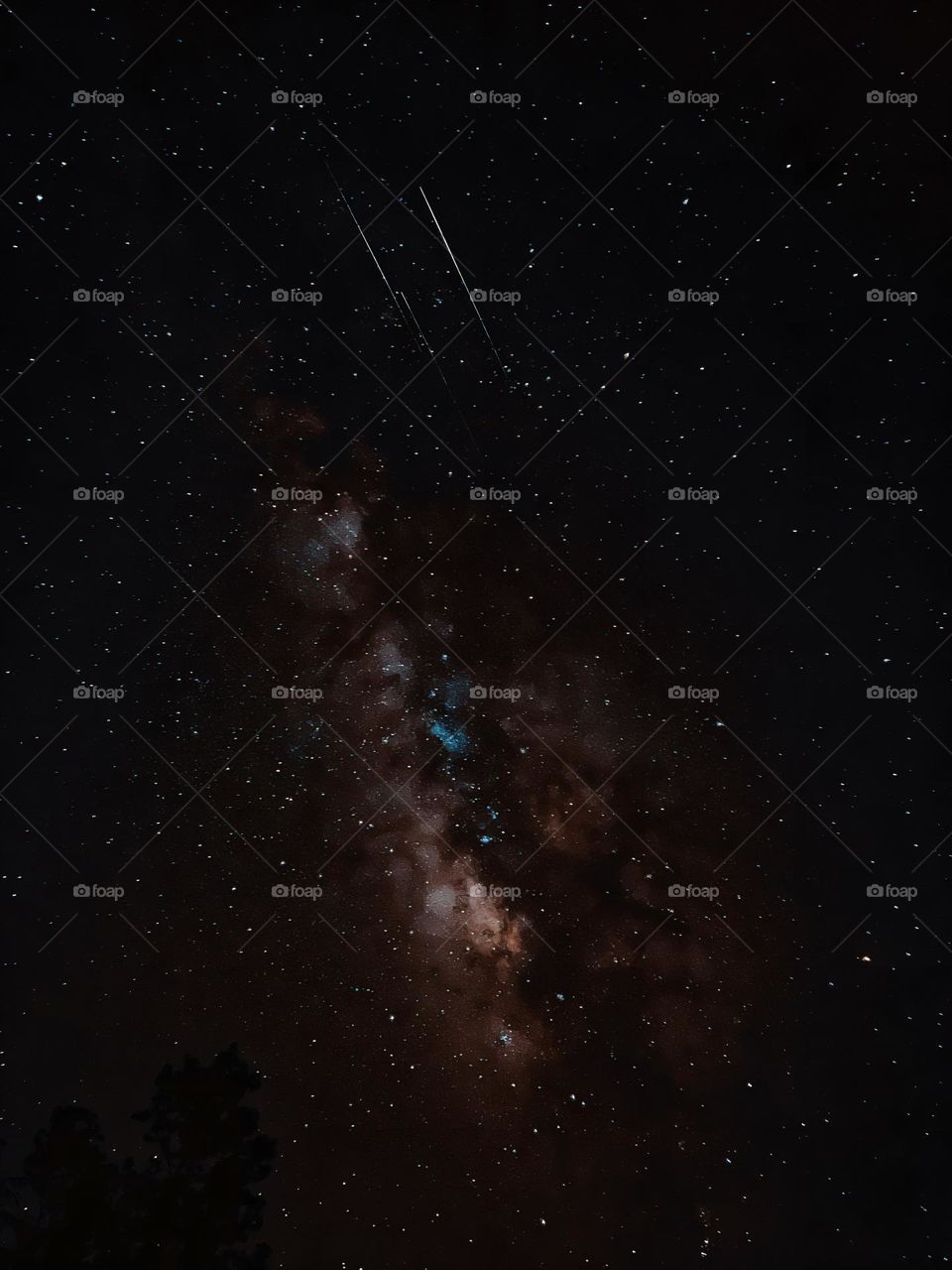 The Milky Way rising as 3 meteors stream past in the night sky.