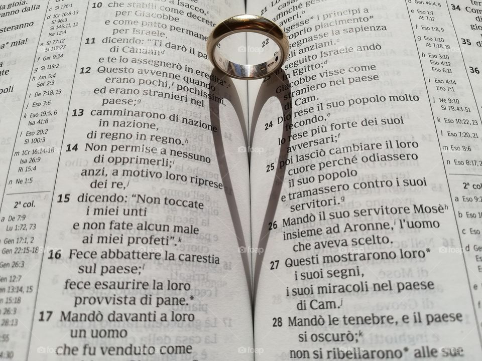 Wedding ring on the Bible forms the shadow of a heart