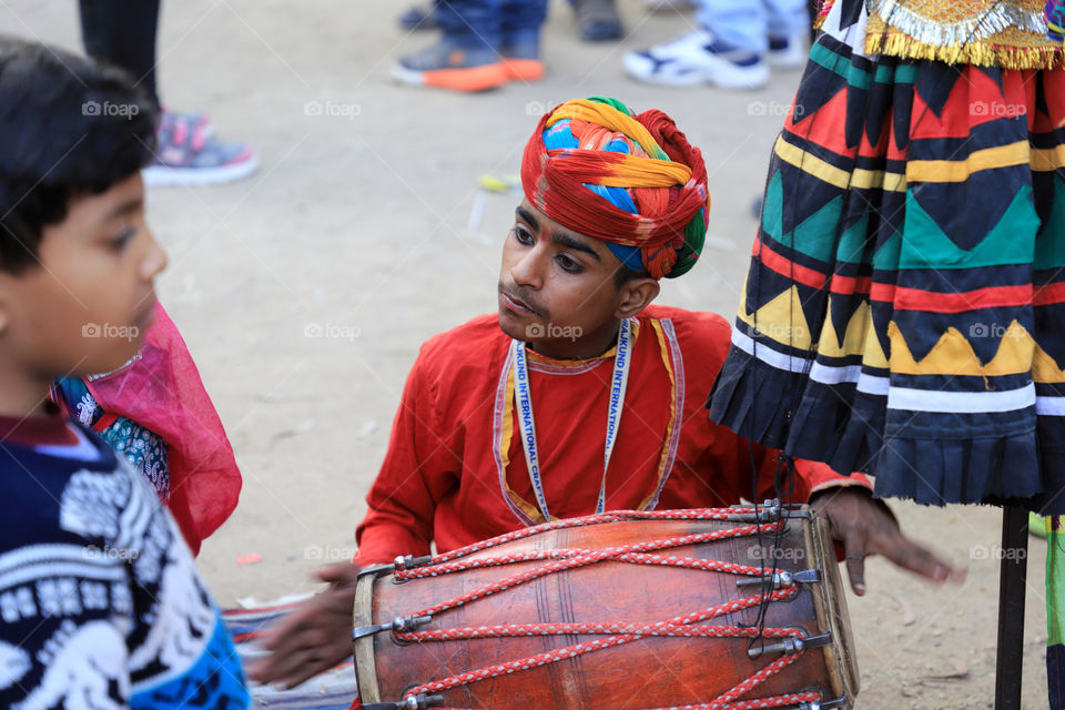 An Indian kid playing traditional drum at surajkund international crafts fair