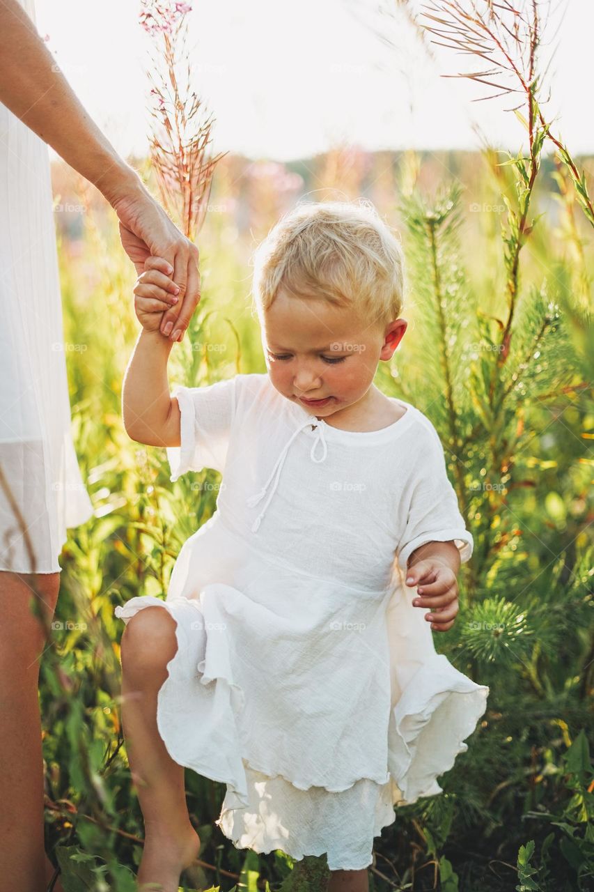 Young woman mother with little girl baby in field on sunset 