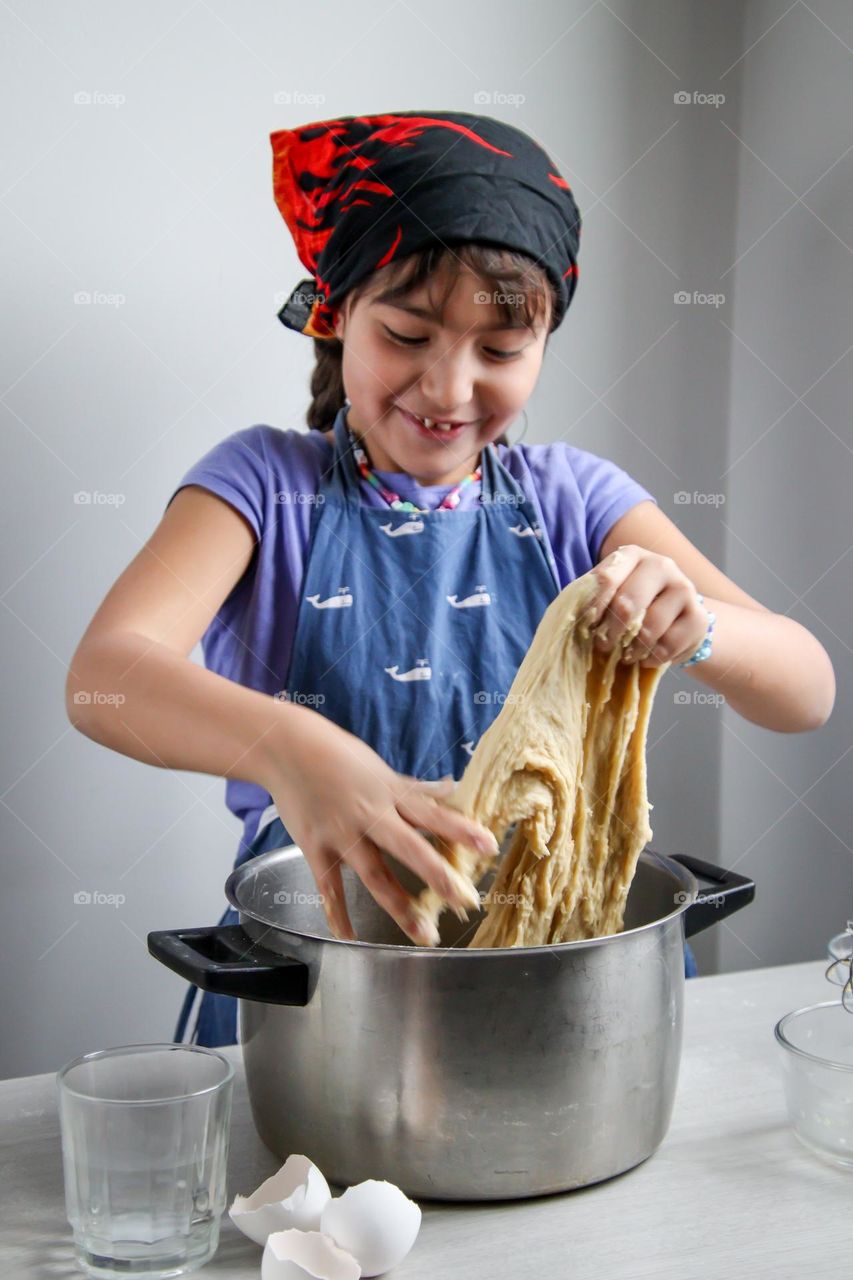 Cute little girl is mixing a bread dough